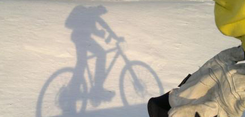 Skuggan från en cyklist i snö.