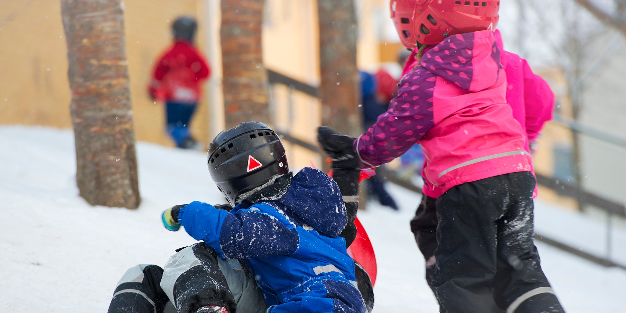 Barn som leker i en snöig backe