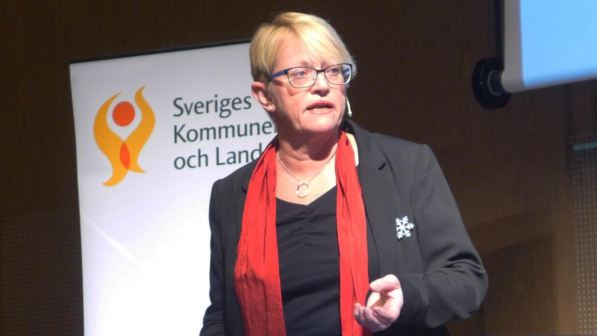 Marie Wieselgren framför en skylt med texten Sveriges kommuner och landsting.