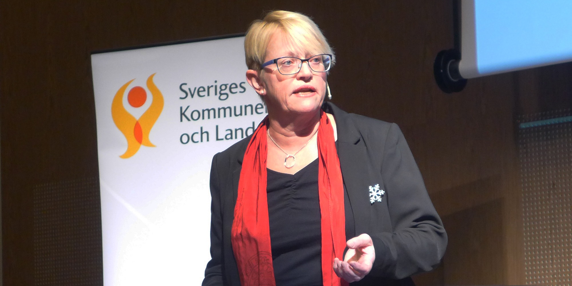 Marie Wieselgren framför en skylt med texten Sveriges kommuner och landsting.