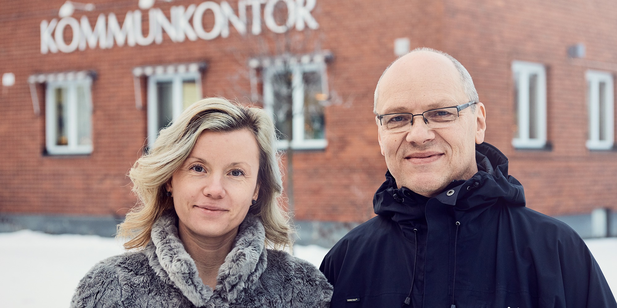 Liza Wikström och Tom Norrgård, Vindelns kommun, står utomhus framför kommunhuset.