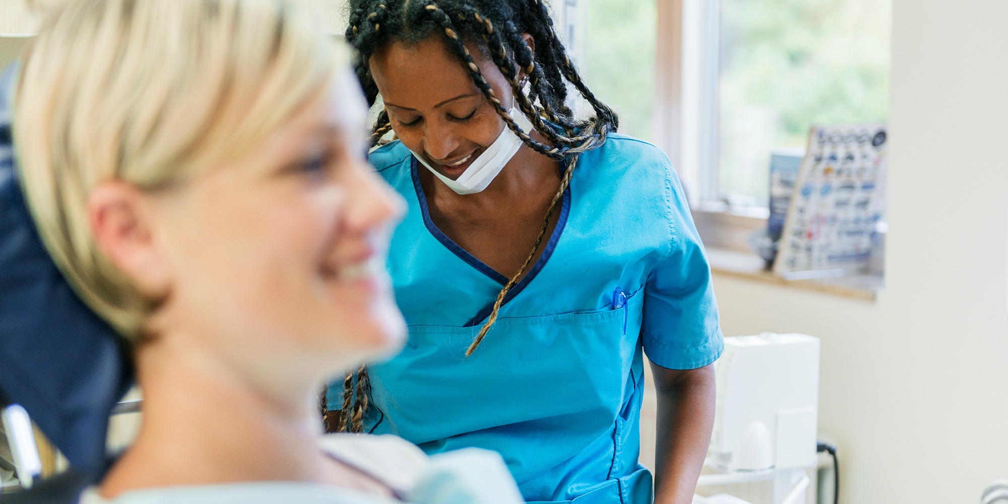 tandläkare med rastaflätor och glad kvinnlig patient