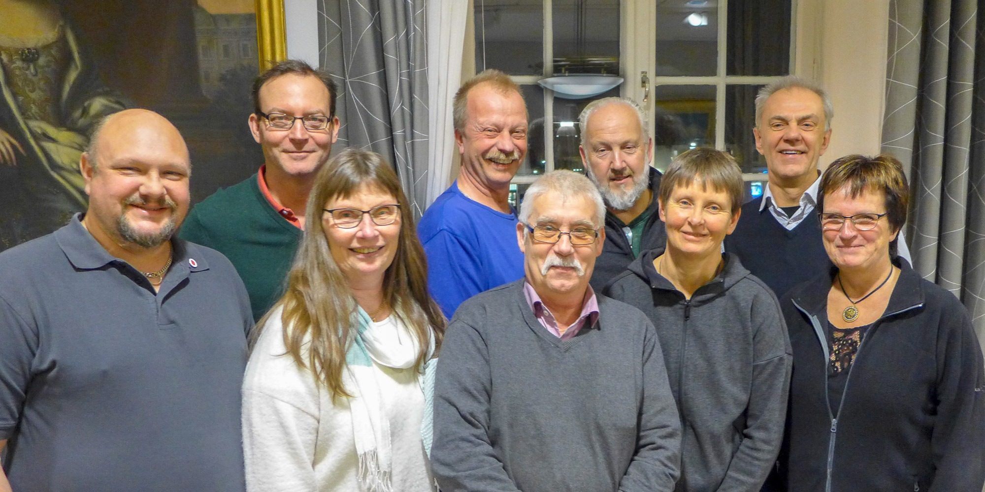 Gruppbild på nio glada personer i medelåldern som står framför ett stort fönster. Personerna är politiker i Askersunds kommun och har gått Suntarbetslivs arbetsmiljöutbildnng.