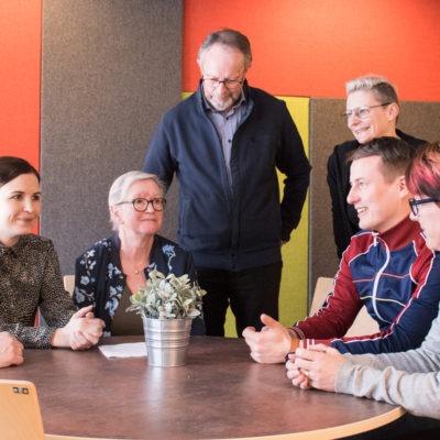 Sju glada personer runt ett bord, delaktighet Uppsala socialtjänst