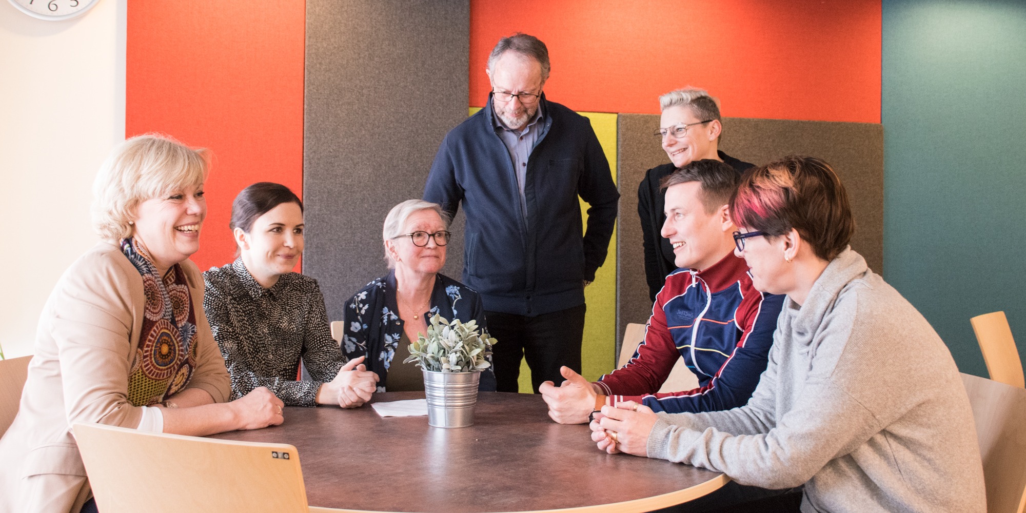 Sju glada personer runt ett bord, delaktighet Uppsala socialtjänst