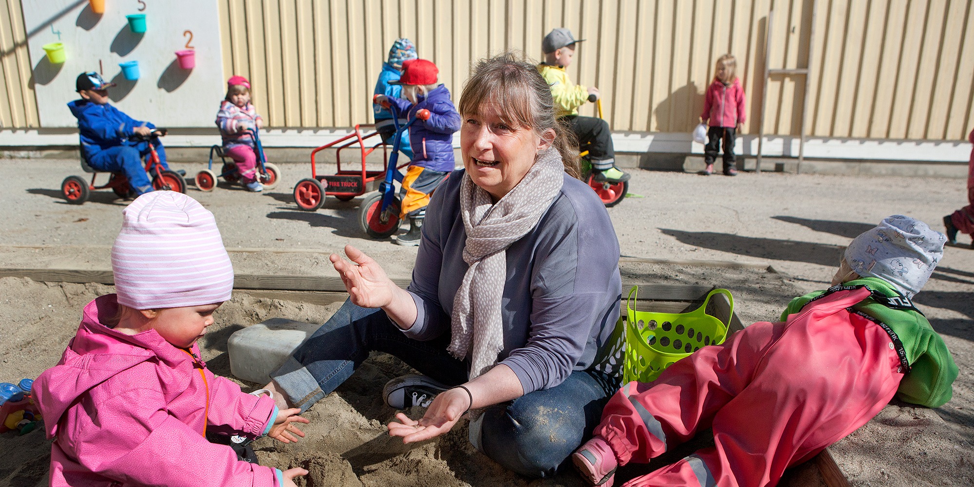 lena berggren förskollärare i Sundsvall, sitter i en sandlåda tillsammans med förskolebarn