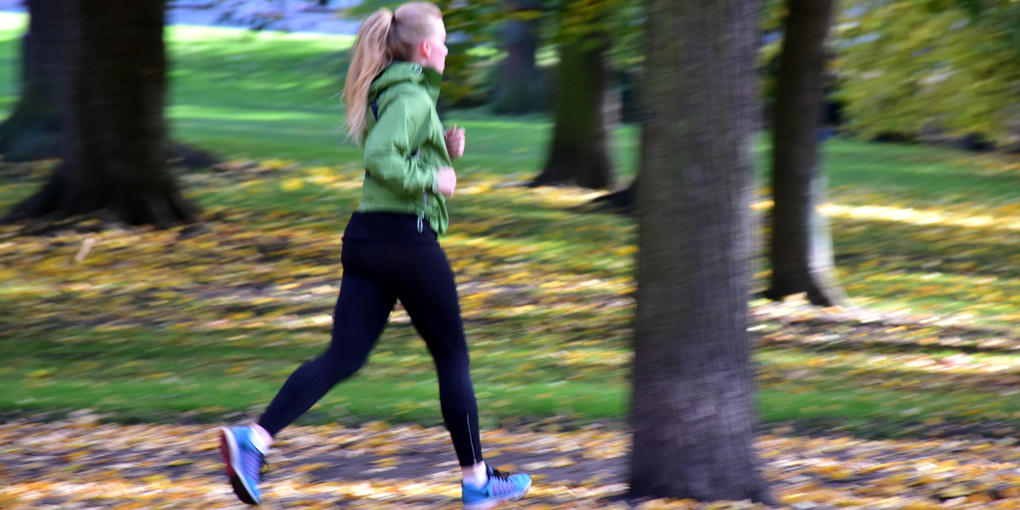Kvinna joggar i parkmiljö.