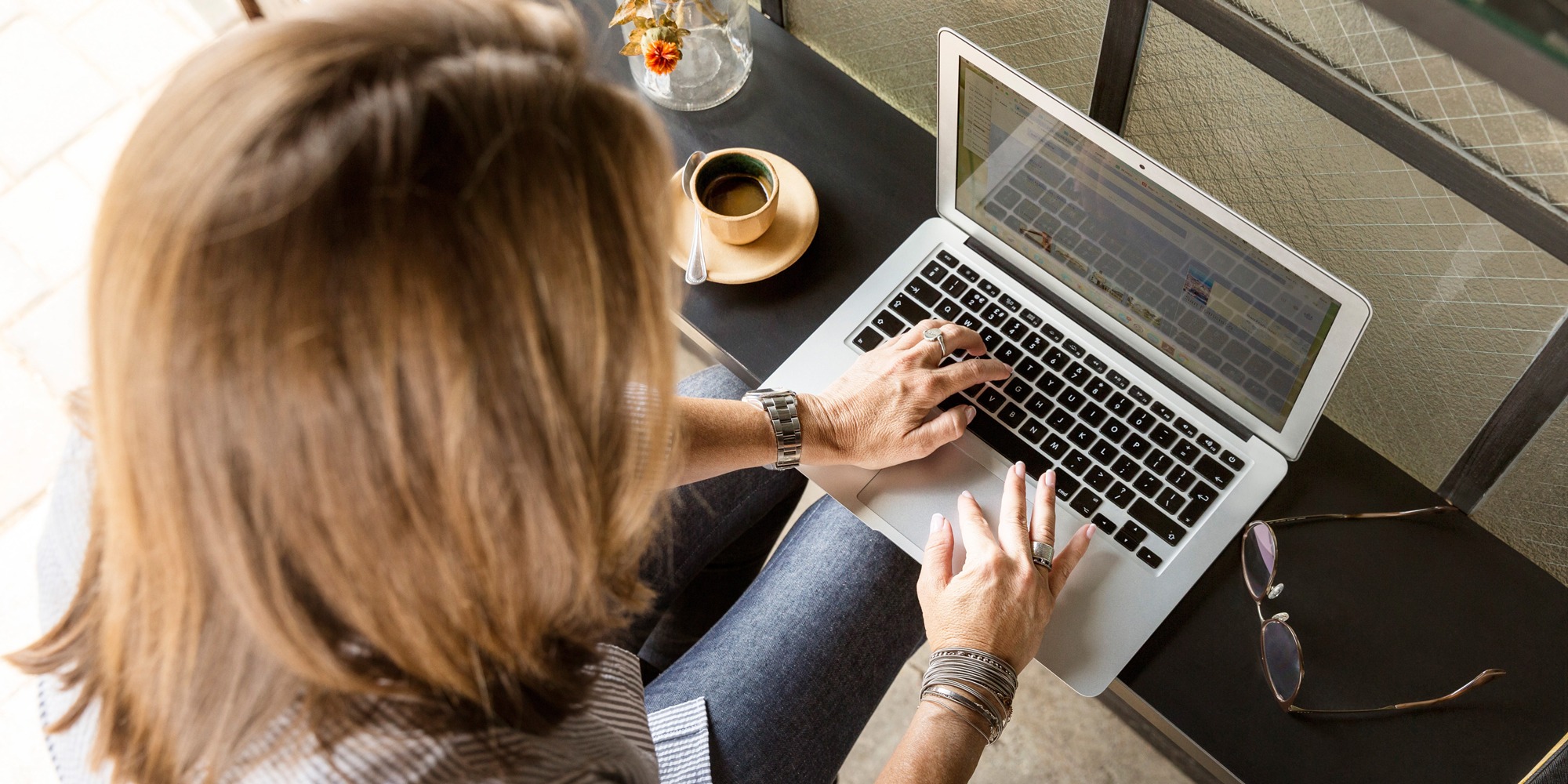 Sittande kvinna skriver på laptop, bättre dokumentation för socialsekreterare.