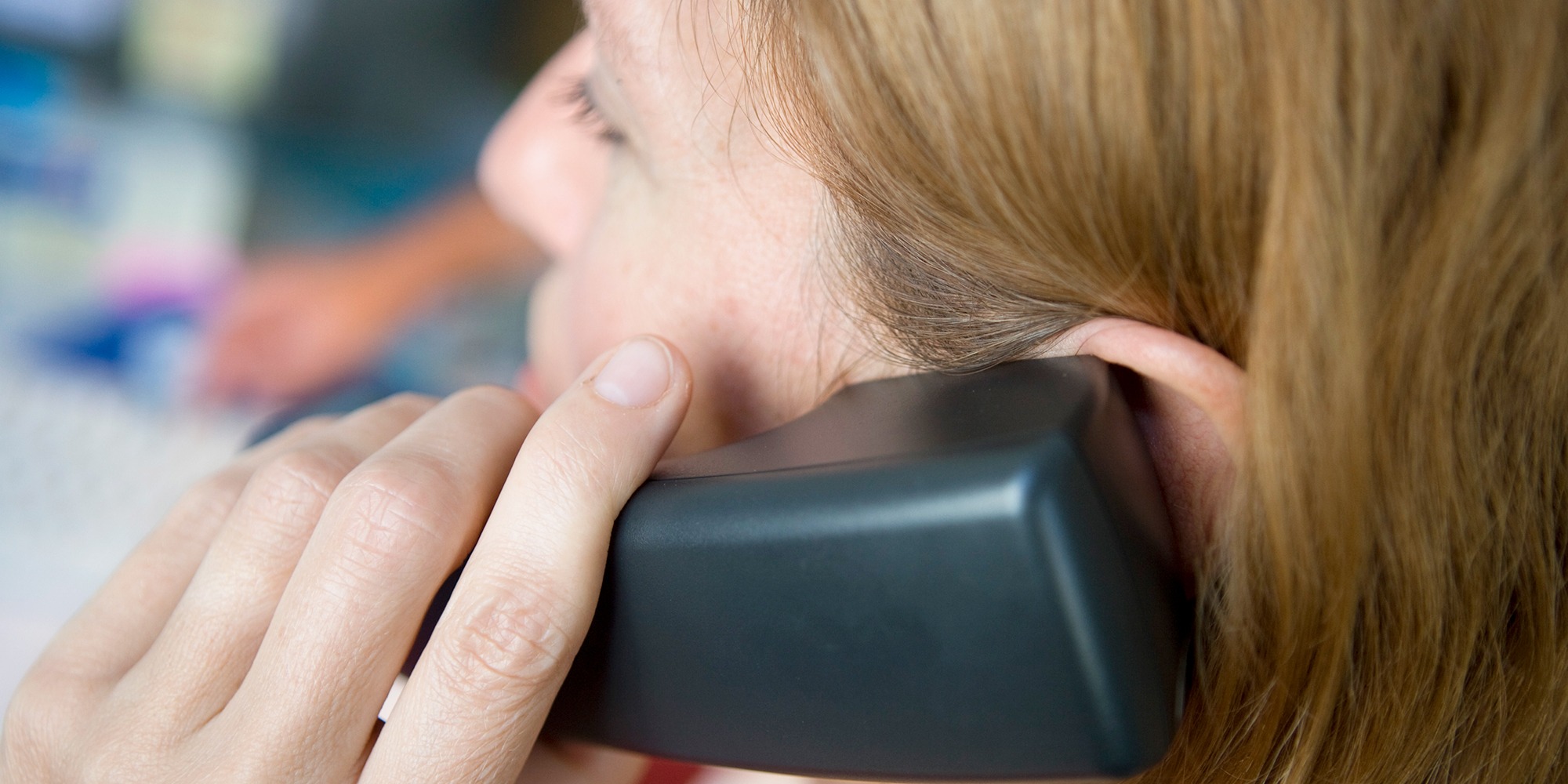 kvinna i rött hår talar i telefon. sedd snett bakifrån.