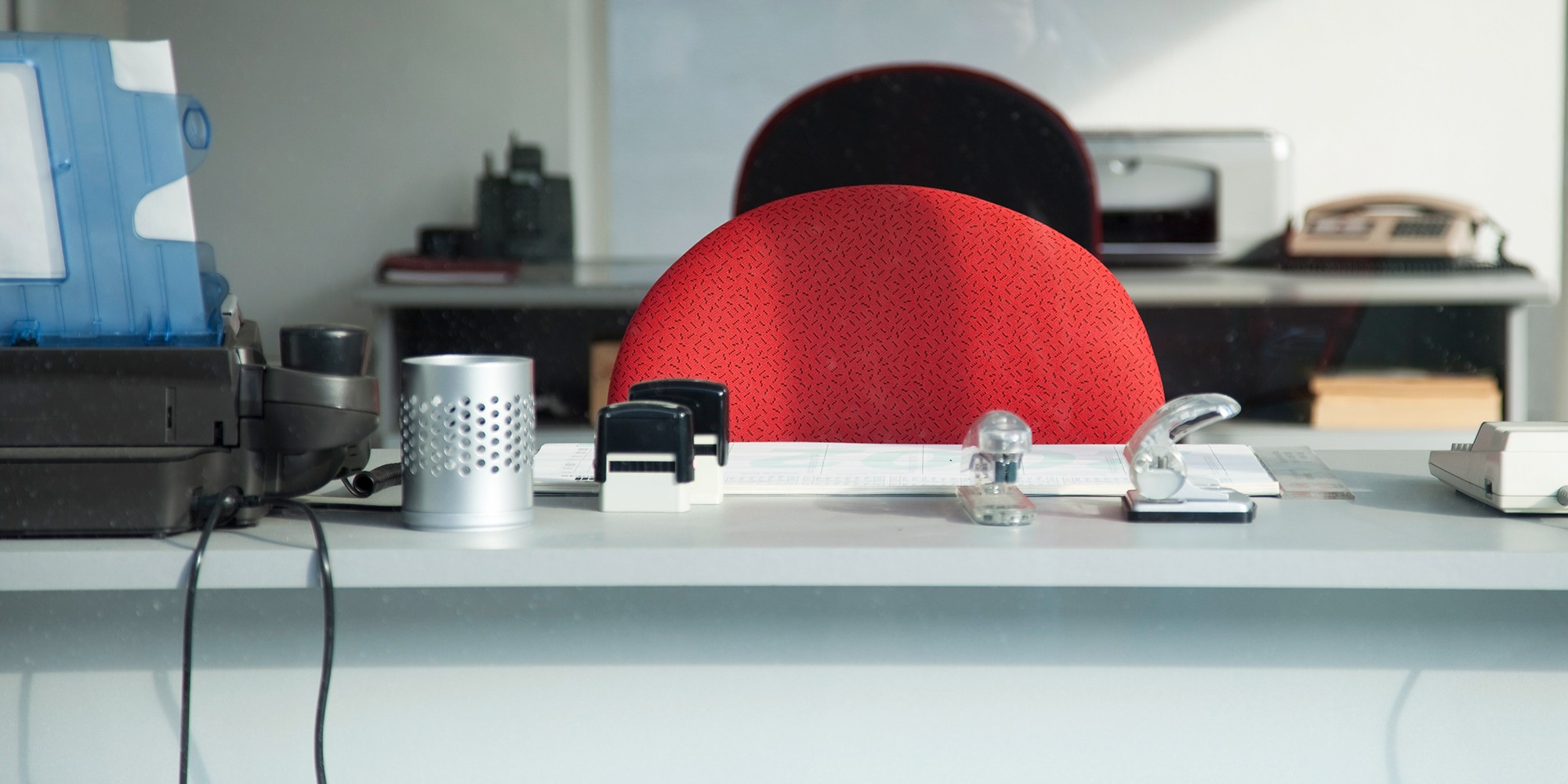 ett vitt tomt skrivbord med röd stolsrygg, sett framifrån.
