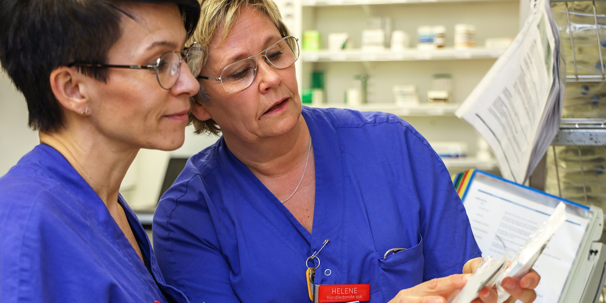 handledning på medicinavdelning 6 på Skaraborgs sjukhus i Lidköping. Två kvinnor i sjukhuskläder, den ena visar den andre ett paket med dropp.