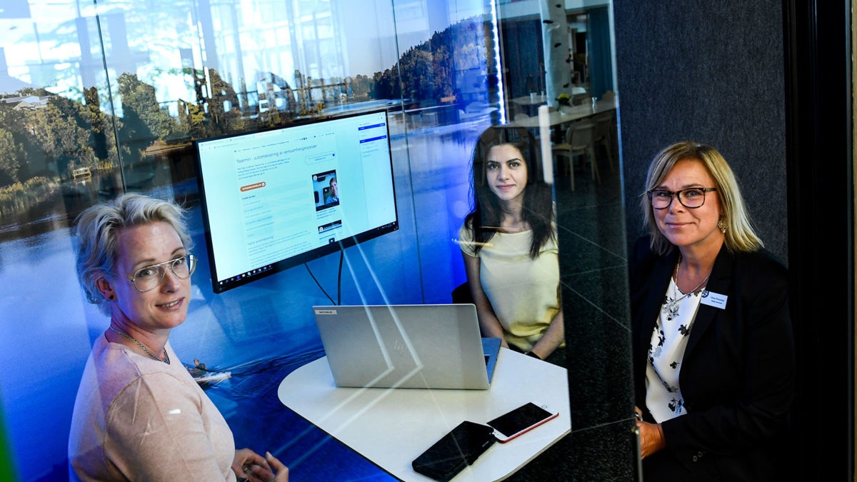 Bild på Malin Jacobsson, Yasemin Esen och Ghita Flinckman som sitter runt ett bord med en dator. Rummet har glasväggar och ser futuristiskt ut.