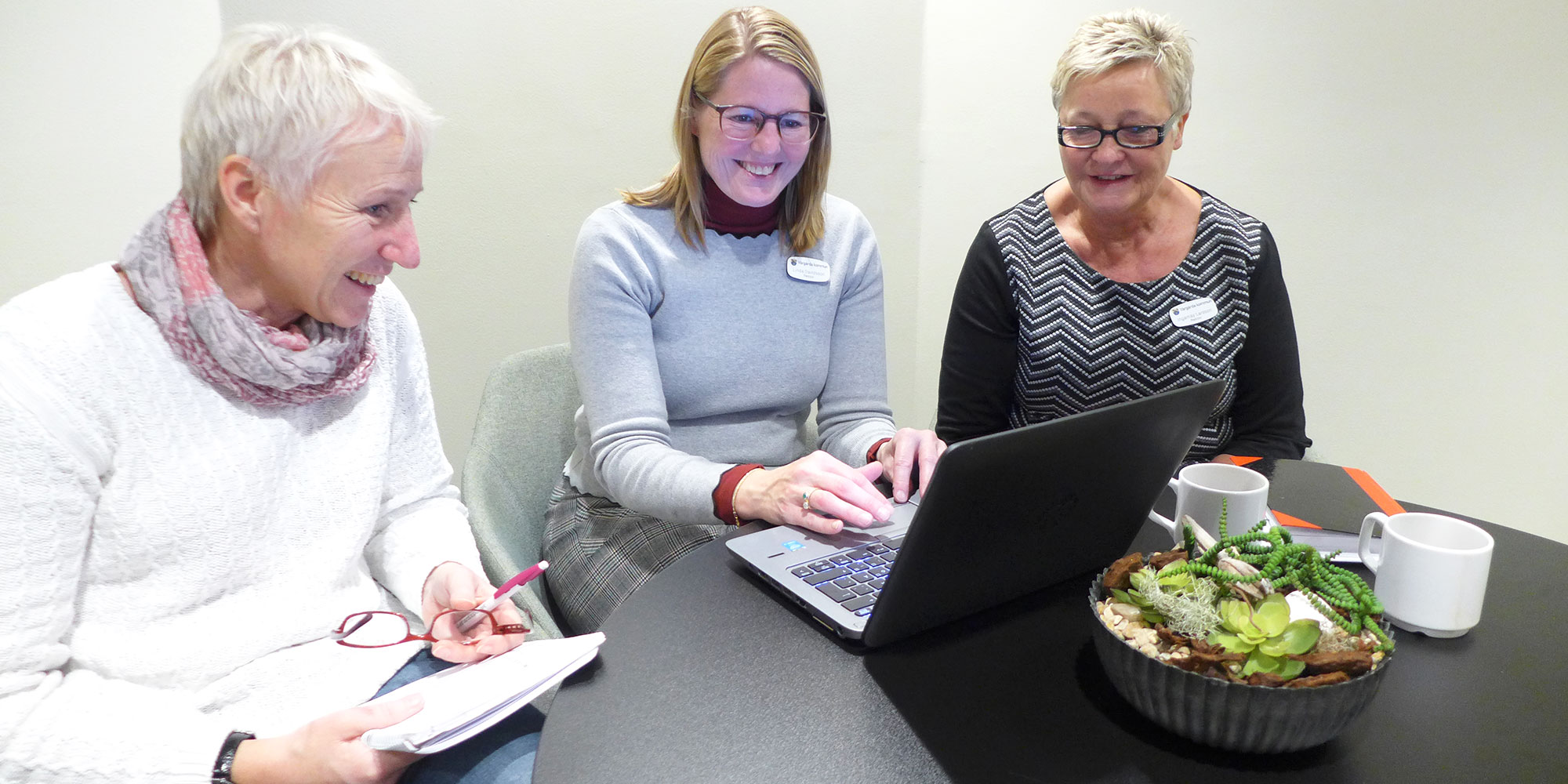 Tre rektorer från Vårgårda kommun sitter och jobbar med en dator vid ett bord. De tre är Karin Andersson, Linda Davidsson, Ingamay Larsson.