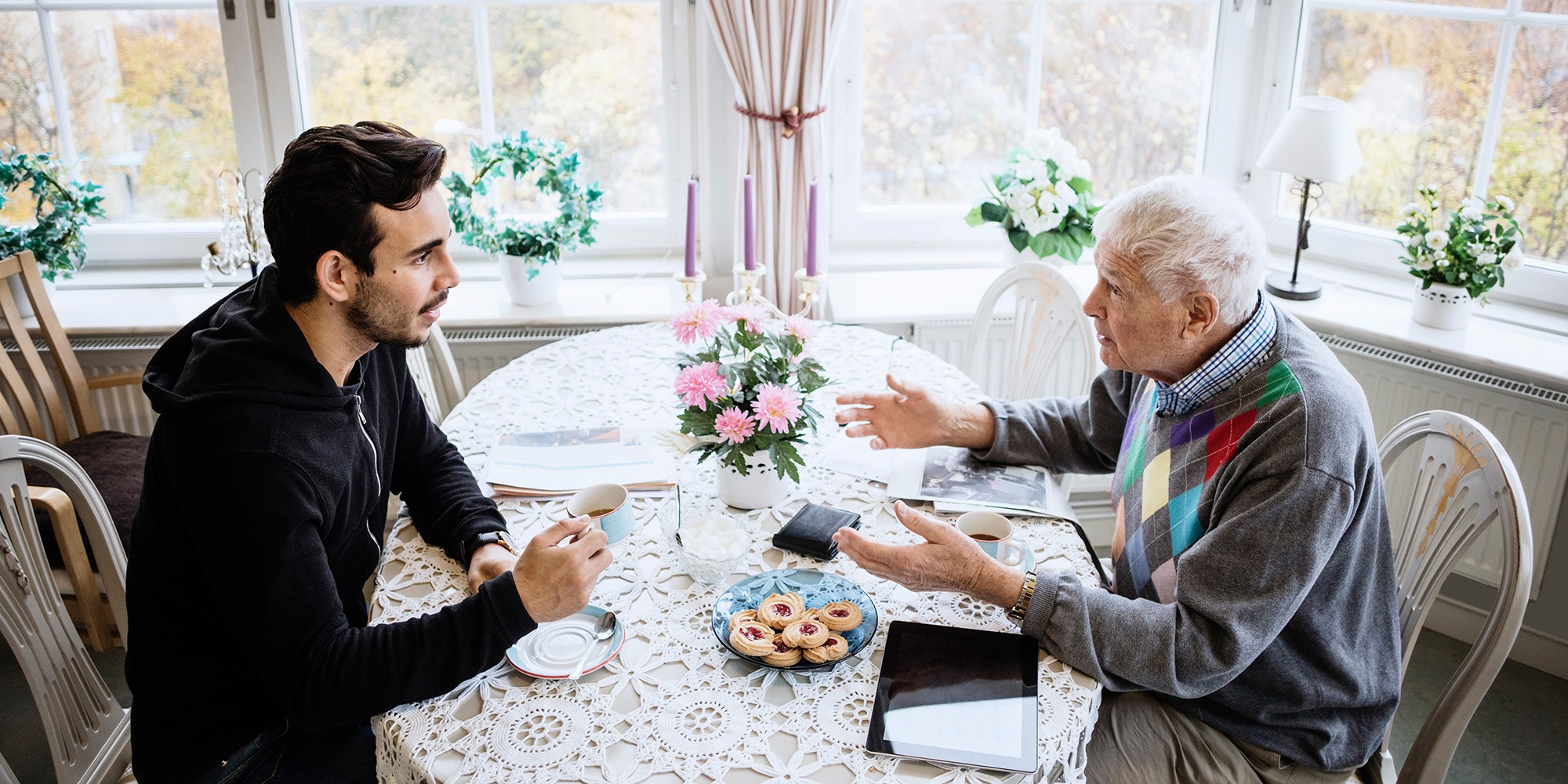 En ung man och en äldre man sitter vid ett bord och pratar.