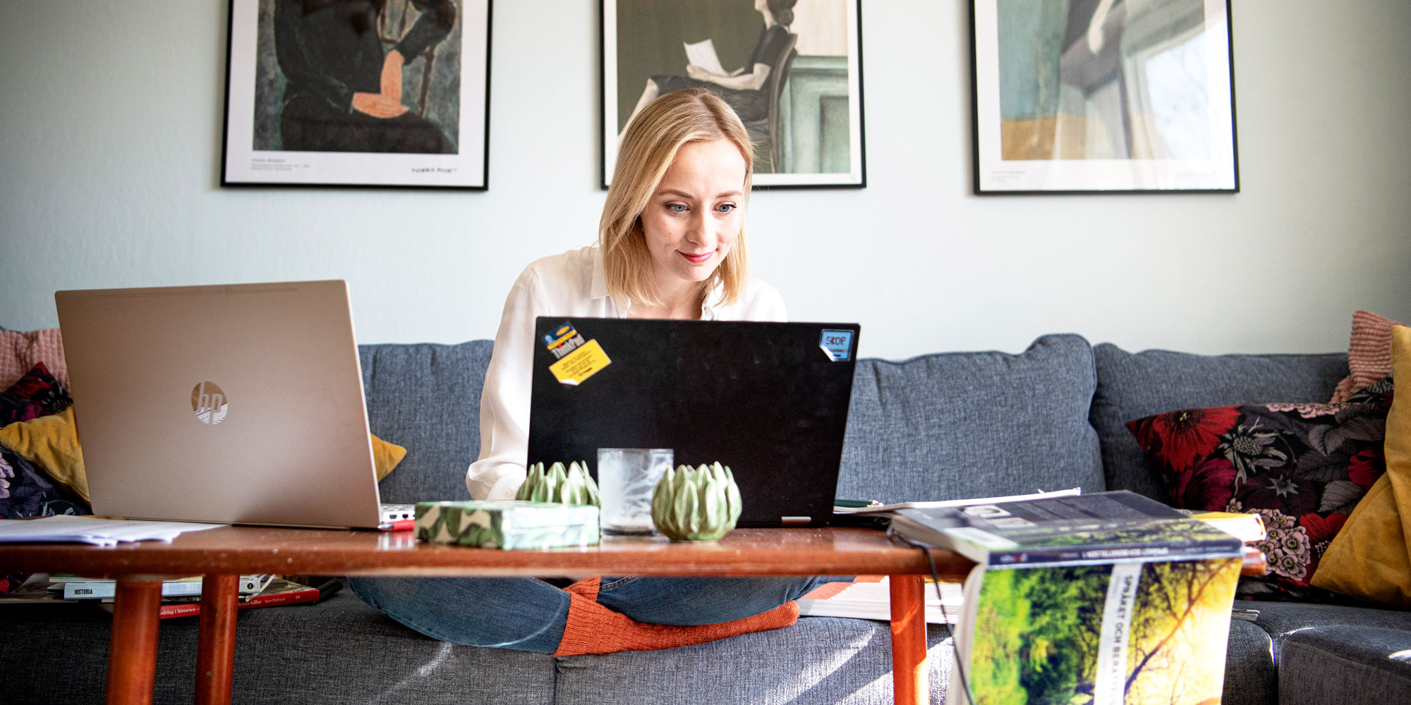 Isabelle Mattlar, skyddsombud på Celsiusskolan i Uppsala, sitter i soffan hemma och jobbar med en bärbar dator. Några tavlor syns på väggen bakom henne.