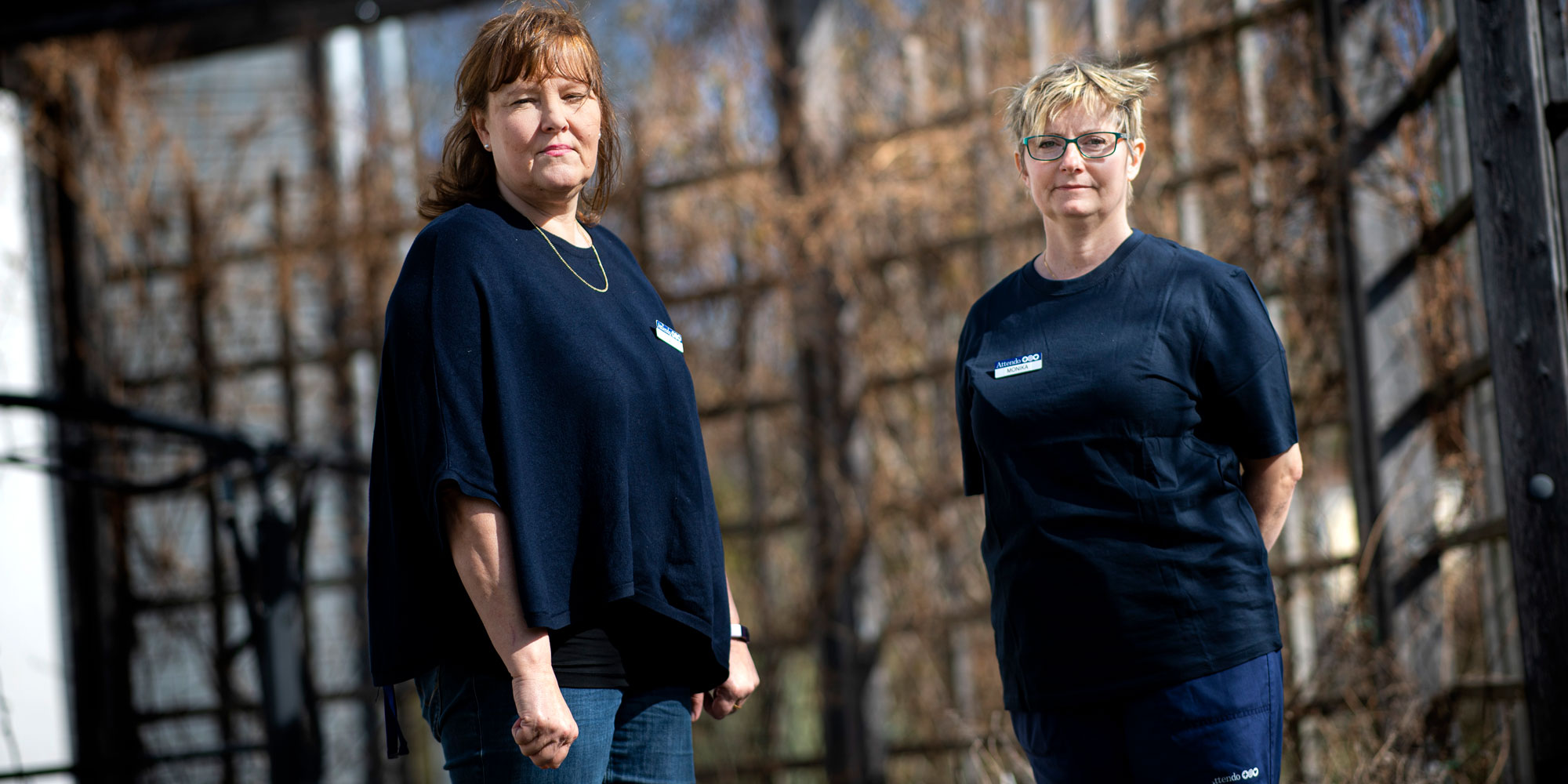 Carina Jällrud och Monika Rivas på äldreboendet Sandelska Huset. Står utomhus i blå arbetskläder.