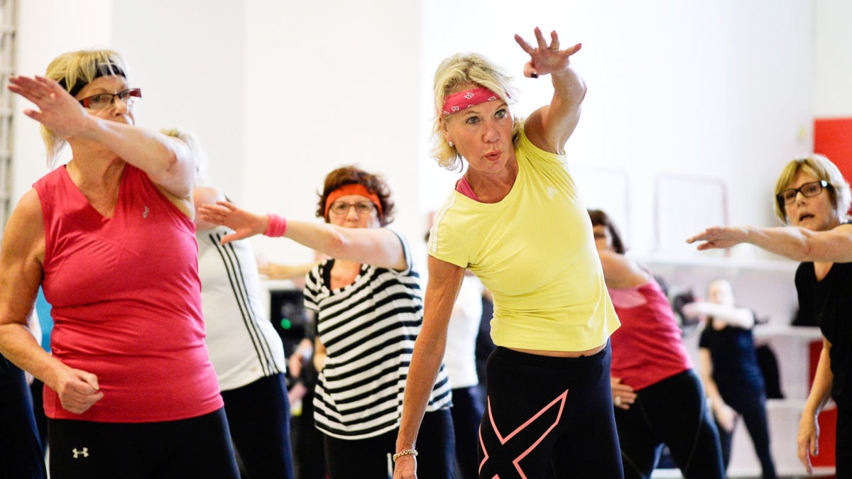 En grupp kvinnor i medelåldern har gympa i en träningslokal.