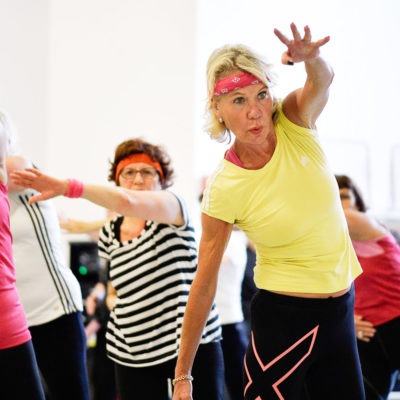 En grupp kvinnor i medelåldern har gympa i en träningslokal.