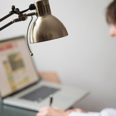 Kvinna vid dator med lampa i förgrunden