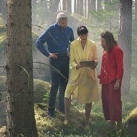 Prehabguiden. En grupp människor med färgglada kläder står i en skog och pratar kring en surfplatta.