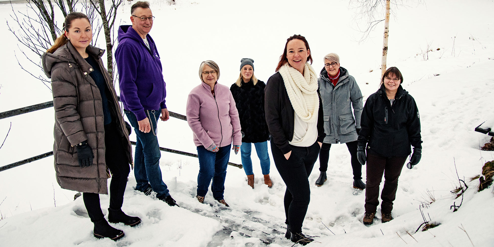 Sju personer från Lyckseles samverkansgrupp står utomhus i en snöig trappa.