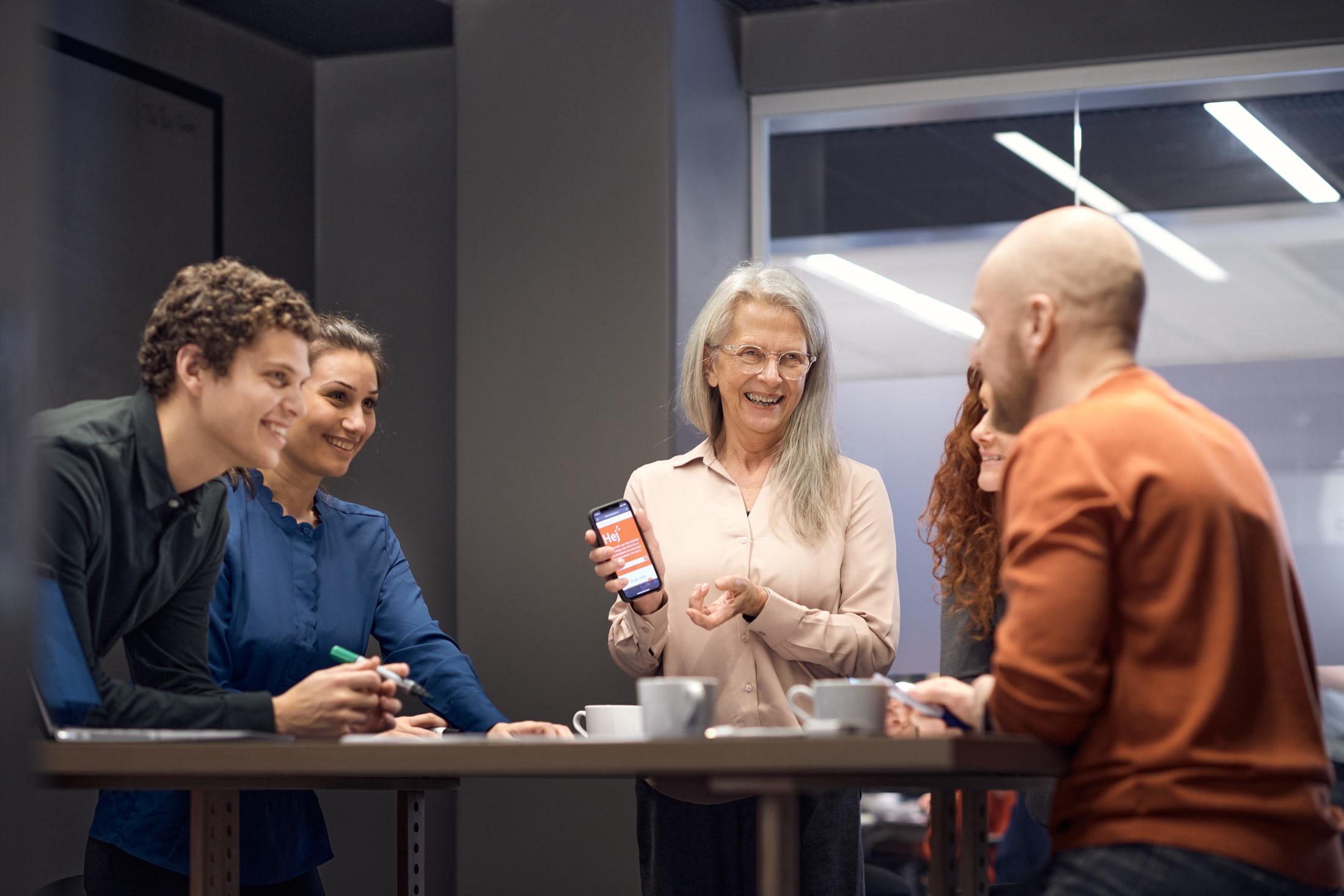 Fyra personer står runt ett konferensbord och samtalar