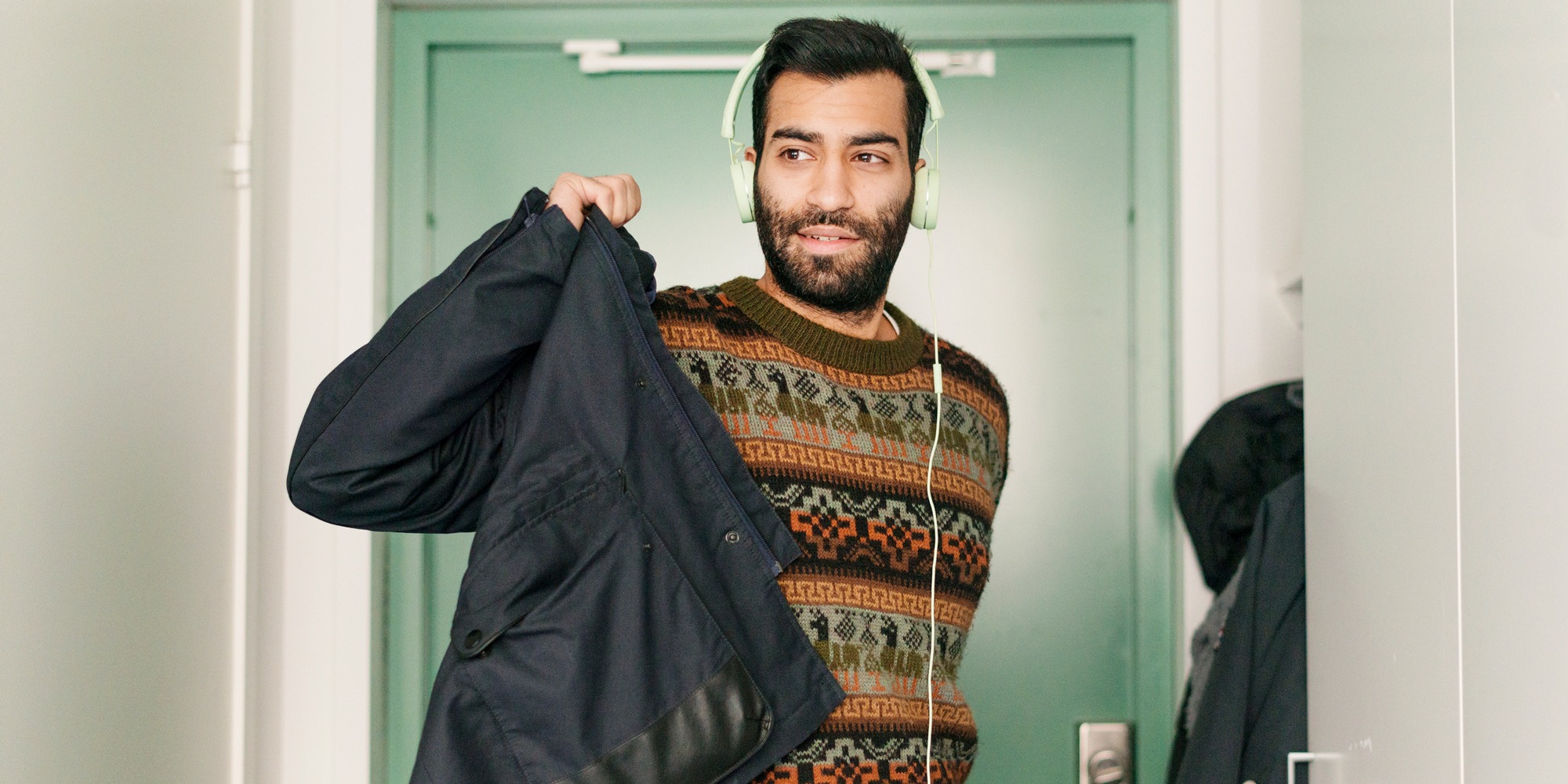 En person med hörlurar på tar på sig en jacka