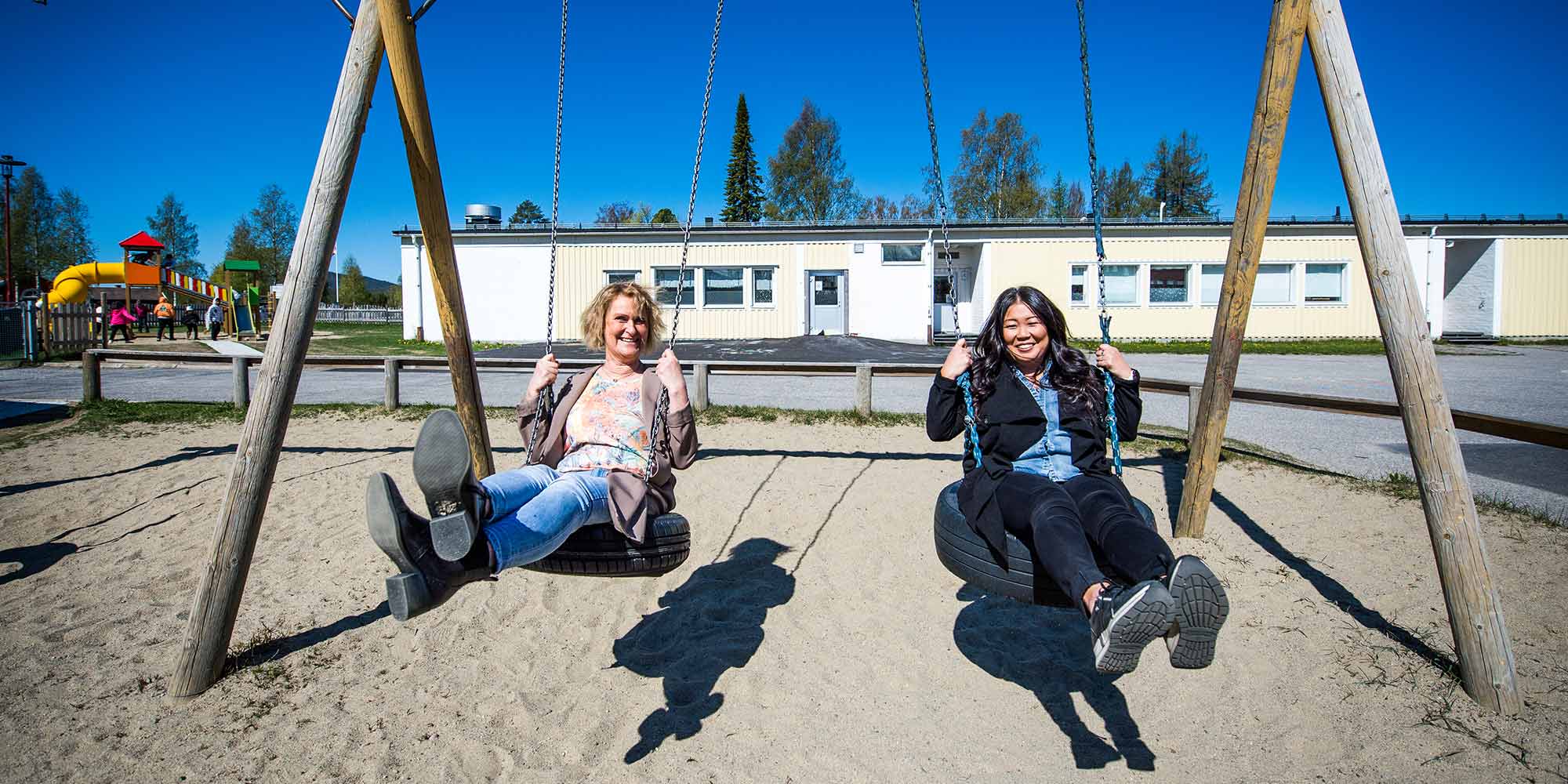 Gunilla Falk och Helena Eriksson gungar på skolgården i Bjurholm.