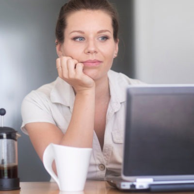 En kvinna sitter vid en laptop och ser avslappnad ut