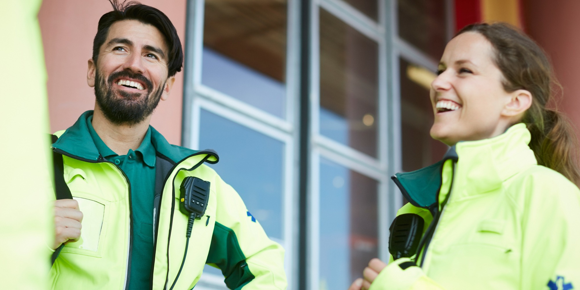 Leende ambulanssjukvårdare står utomhus och pratar.