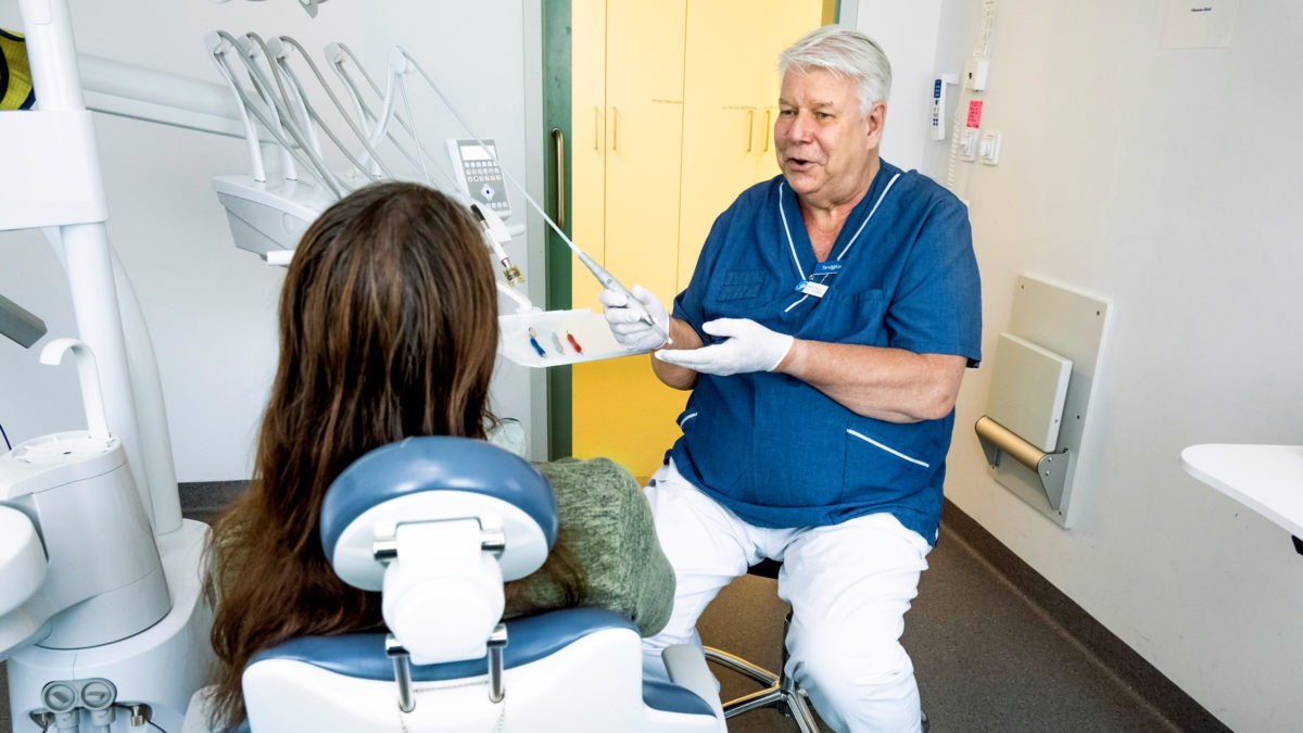 Tandläkaren Niklas Öberg pratar med en patient som sitter i tandläkarstol