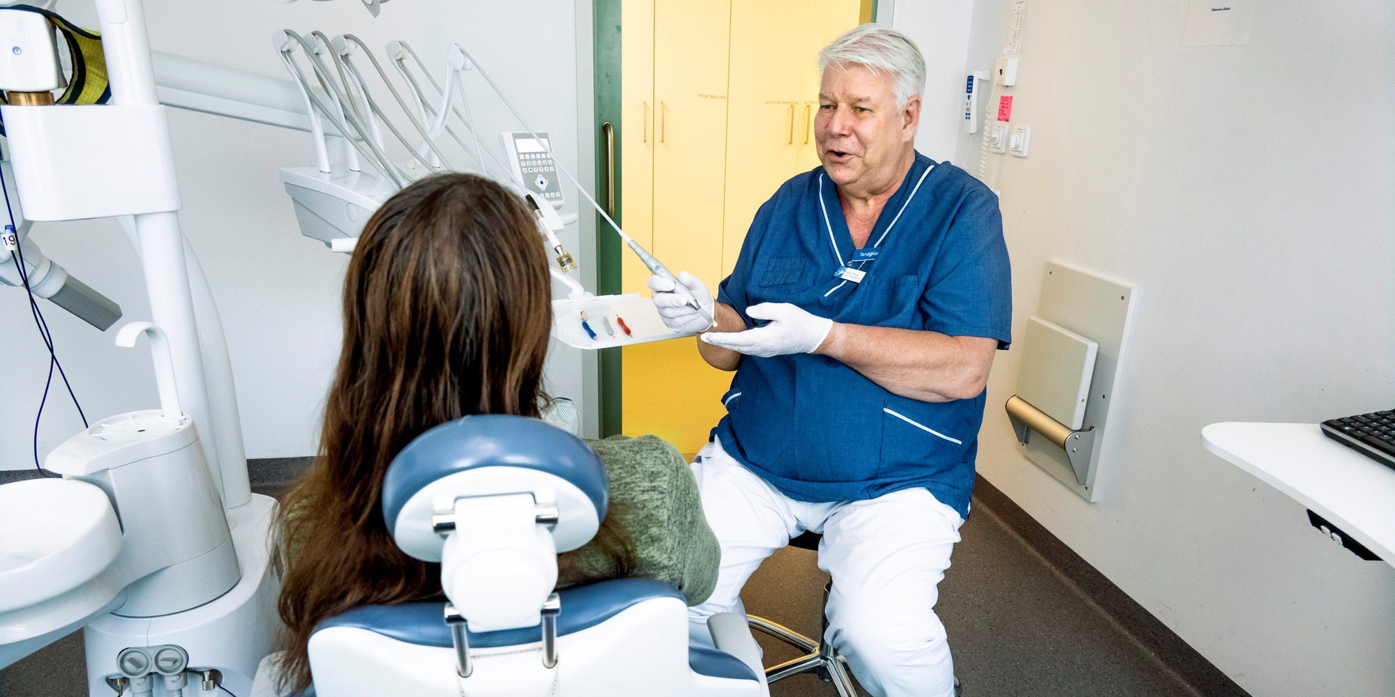Tandläkaren Niklas Öberg pratar med en patient som sitter i tandläkarstol