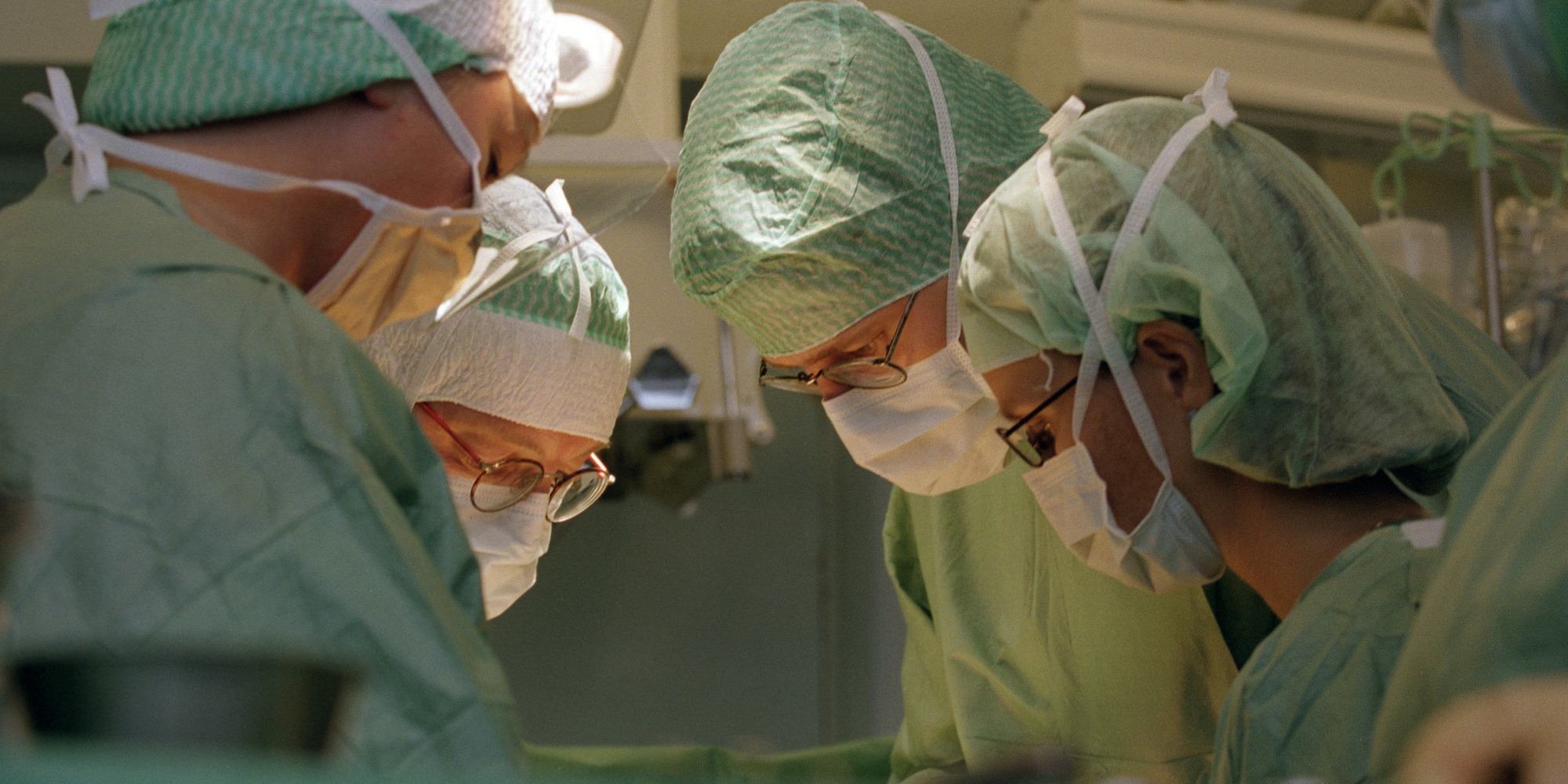 Fyra läkare lutar sig över ett operationsbord