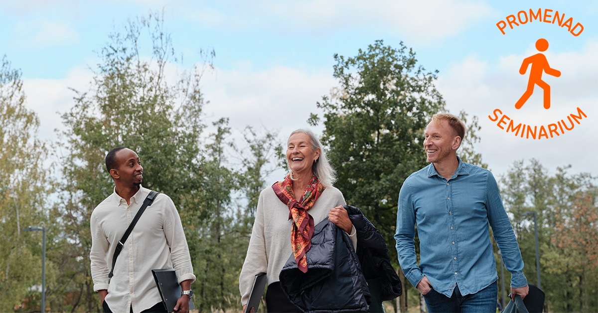 Tre personer promenerar och skrattar i utomhusmiljö.