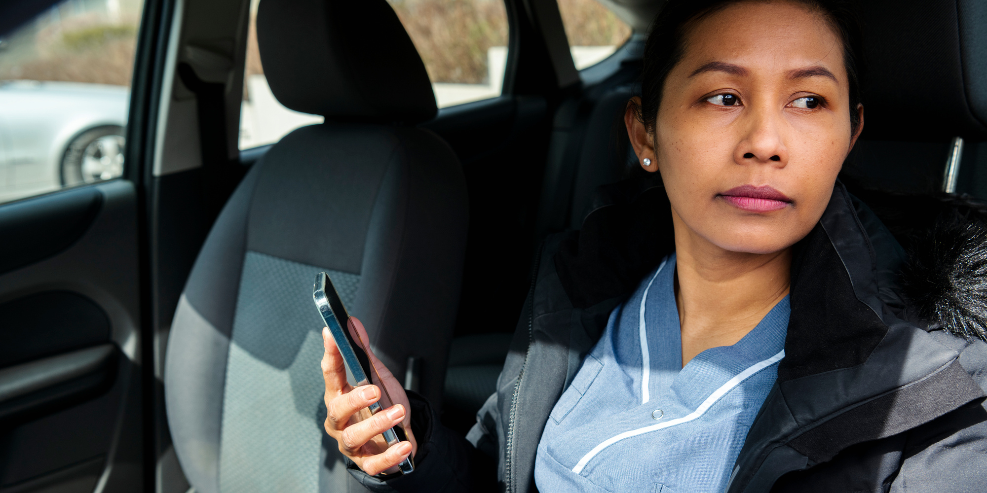Kvinnlig hemtjänstpersonal med mobil i bil