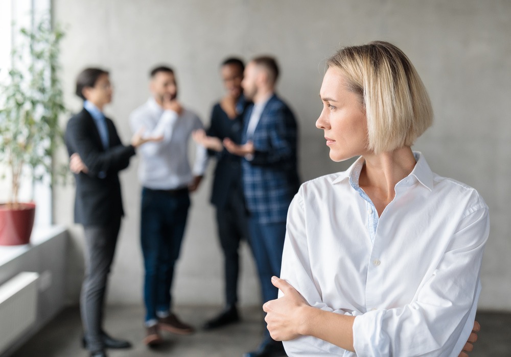 Fyra män står i grupp och talar. En ensam kvinna i förgrunden.