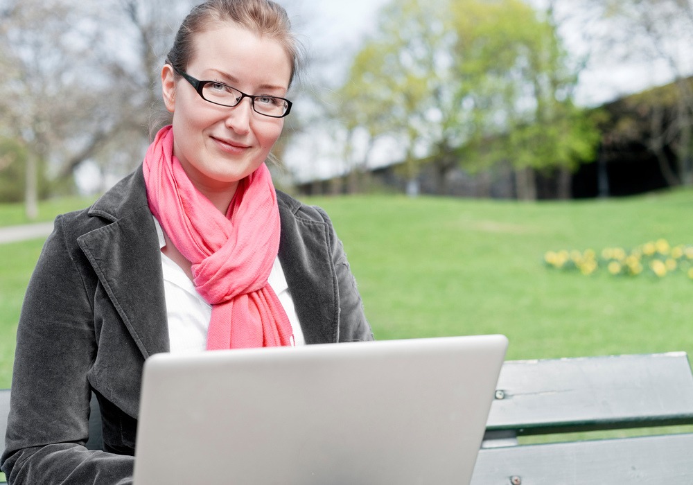 Kontorsarbete ute. En kvinna med dator i en park