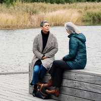 två kvinnor sitter och talar med varandra på en brygga: Säkerhetsdialogen