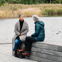 två kvinnor samtalar på en brygga i höstligt väder