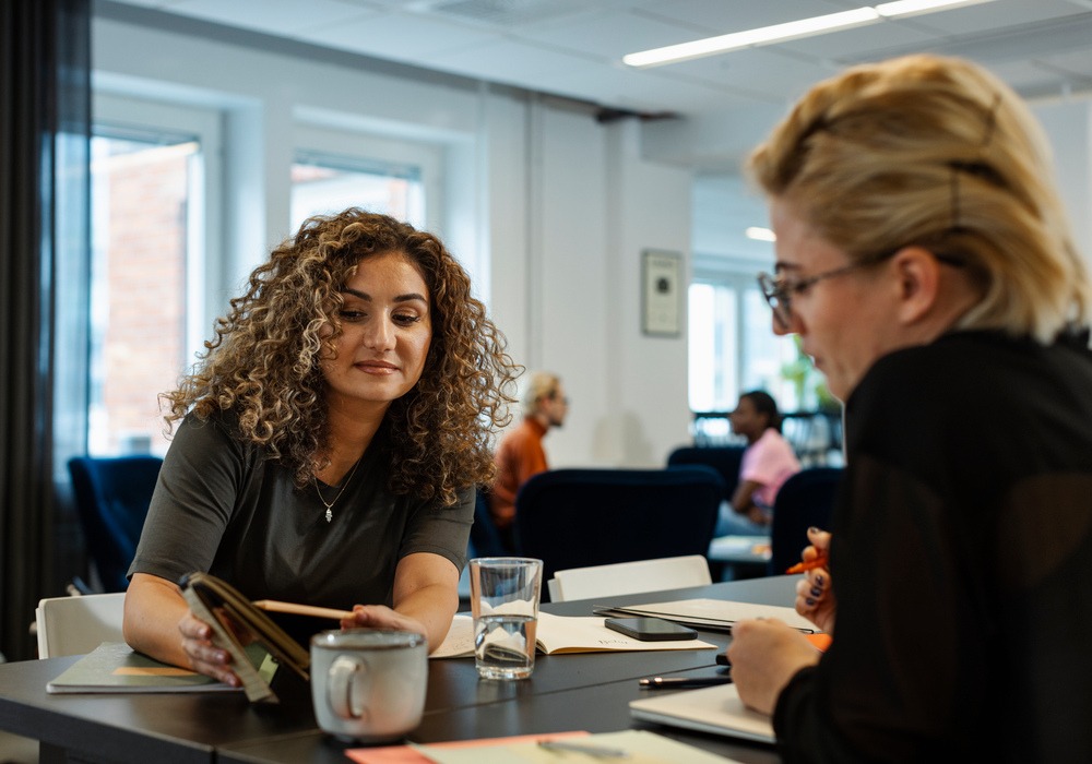 Två kollegor på kontor pratar med varandra