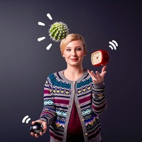 En kvinna jonglerar med en kaktus, en klocka och en svart boll.