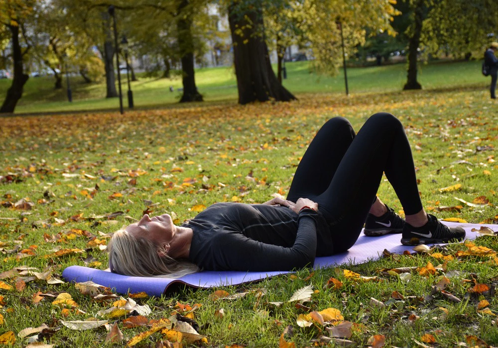 Kvinna vilar sig i gräset, illustrerar myter om utmattningssyndrom.