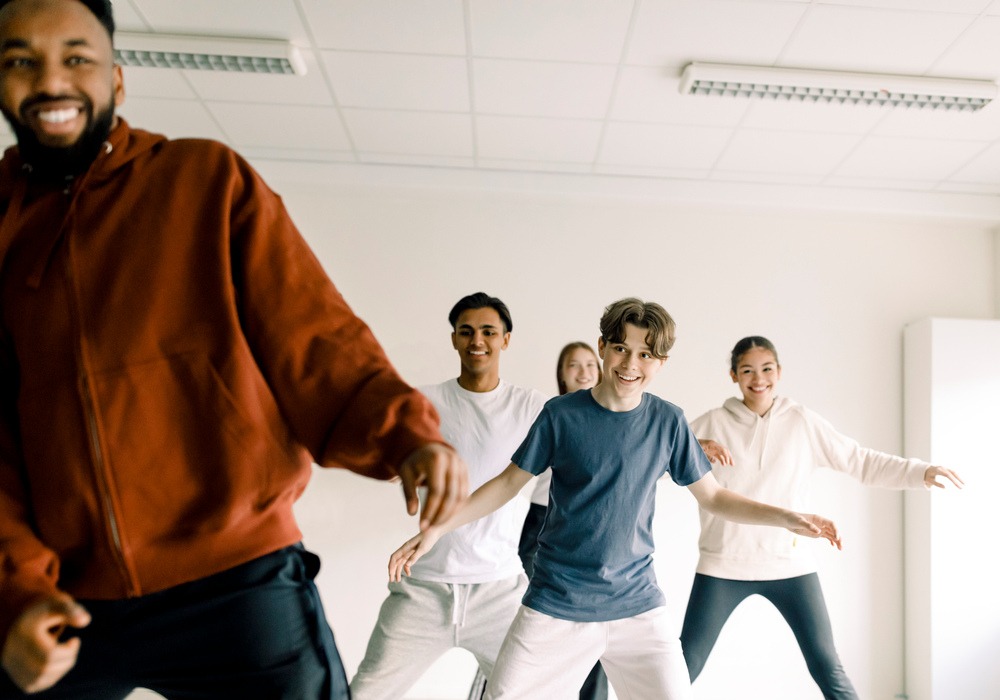 leende ung danslärare visar en grupp tonåringar hur man dansar