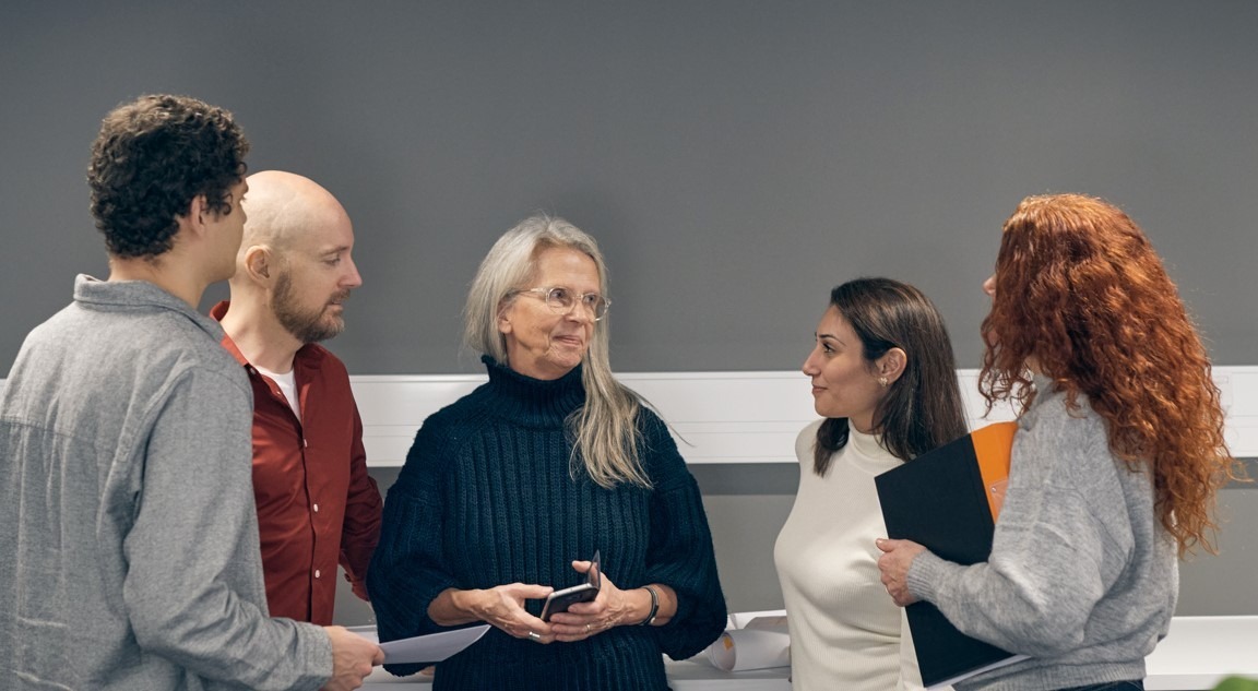 Fem personer står i grupp och samtalar.