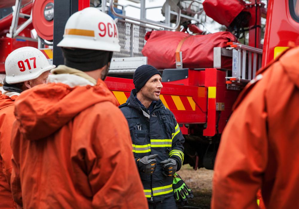 Brandmän som pratar framför brandbil.