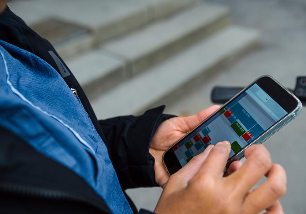 Kvinnlig hemtjänstpersonal tittar på schema på mobil, tema digitalisering i kommuner.