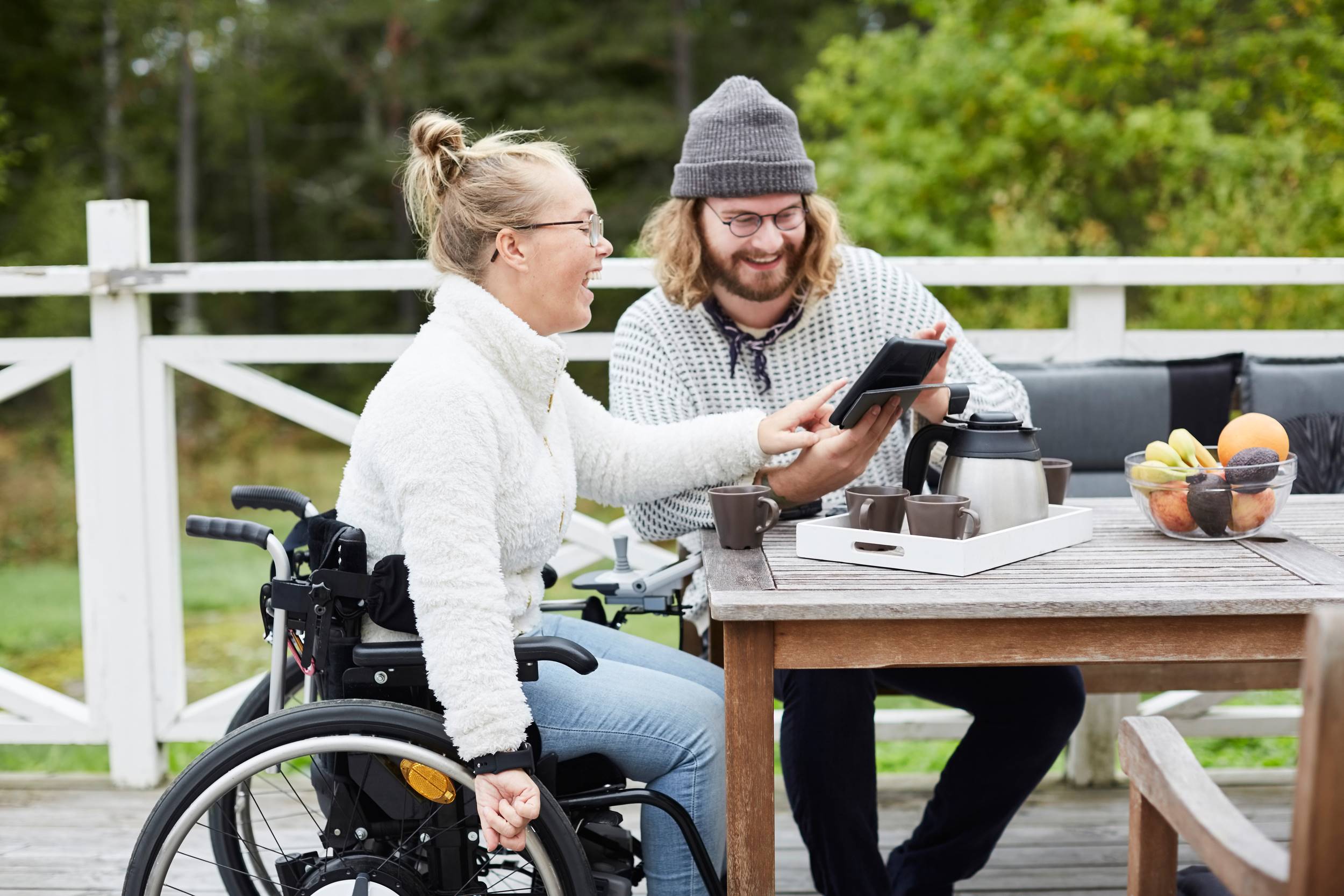 En man som jobbar som personlig assistent tittar på en läsplatta tillsammans med en ung kvinna i rullstol. Han har 11 timmars dygnsvila mellan sina arbetspass.