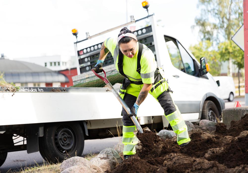 Klimat och arbetsmijö. Parkarbetare jobbar med rabatt utomhus på sommaren