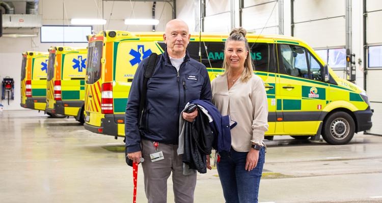 Man och kvinna står i ambulanshall och tittar mot kameran.