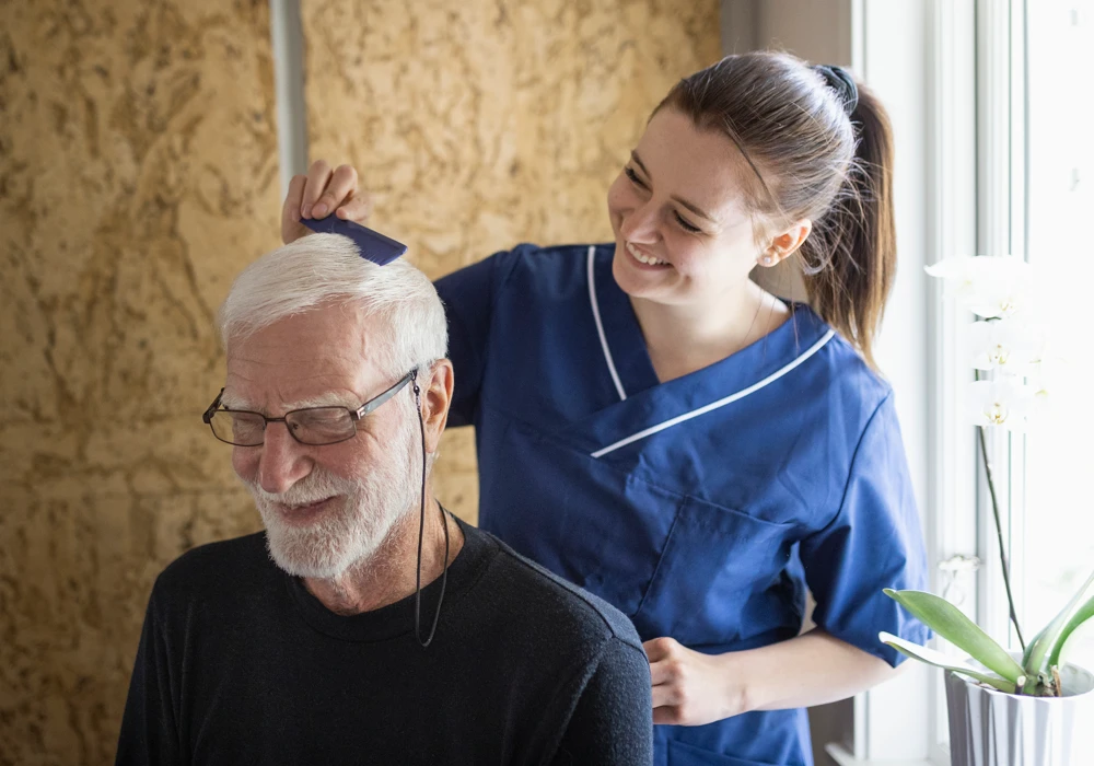 En sköterska hjälper en patient med hans hår.